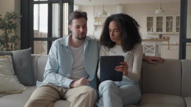 İnternetten alışveriş yapan çift tableti incelerken anlaşmak için çabalıyor. Etkileyici jestler, tepkiler Oyuncu Anlaşmazlıkları Gösteriyor, Gerçekçi Yaratıcılık ve Evde Karar Verme Sahnesi