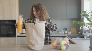 Kıvırcık Kadın, alışveriş gezisinden sonra mutfak tezgahında Taze Market Düzenliyor. Sağlıklı Yaşam Tarzı Konsepti, Modern Mutfakta Organik Meyve ve Sebzelerle Yemek Hazırlama