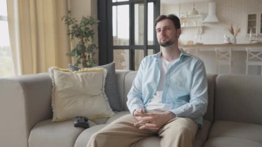 Koltukta oturan adam oyun kontrolörünü kaldırıyor ve video oyunu oynamaya başlıyor. Evde eğlenen sıradan bir oyuncu, Parlak Modern Oturma Odası 'nda Oyun seansına katılıyor.