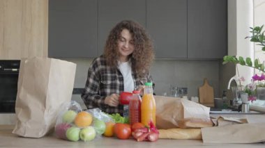 Alışveriş gününden sonra mutfak tezgahında renkli yiyecekler düzenlemek. Kadın Taze Meyveler, Sebzeler, Sıvılar Modern Mutfakta. Sağlıklı Yaşam Tarzı, Ev Rutini Konseptleri İçin Mükemmel Sahne