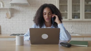 Kadın, ev mutfağında önemli bir iş görüşmesi yaparken dizüstü bilgisayara odaklanmış. İş günü boyunca kendinden emin uzaktan kumandalı işçiler, üretkenlik için rahat iç mekan ve doğal ışık ile çevrili.