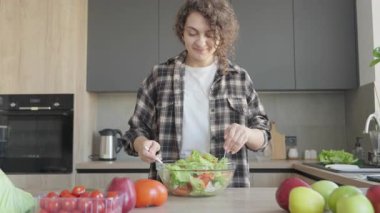 Modern mutfakta taze sebze salatası hazırlayan genç bir kadın. Sağlıklı Yemek Pişirme Süreci, Organik Malzemeler, Ev Hayatı, Temiz Yemek, Doğal Gıda Hazırlama, Parlak İçişleri