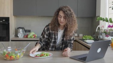 Modern mutfakta salata yiyen ve gülümseyen bir kadın. Neşeli Uzaktan İletişim, Sağlıklı Yaşam Tarzı, Konforlu Ev Sahnesi, Sıradan Bağlantı, Dengeli Günlük Düzenleme