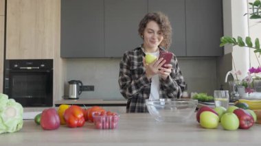 Parlak Mutfak Ayarları 'nda telefon başında heyecan verici haberleri kutlayan kadın. Neşeli Tepki, Mutlu Sabah Anı, Pozitif Enerji, Gerçek Duygu, Doğal Işık, Sıradan Yaşam Tarzı, Dijital Bağlantı