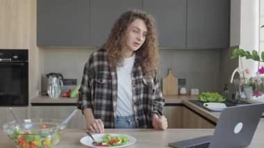 Salata tabağının yanında dururken mutfaktan görüntülü arama yapılmış. Modern Yaşam Tarzı Anı Uzaktan Çalışma Esnekliği, Sağlıklı Yeme Alışkanlıkları, Ev Atmosferi. Yüksek kalite 4k görüntü