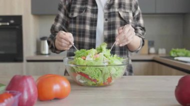 Sağlıklı yaşam tarzı için parlak ve rahat mutfağa taze sebze salatası atıyorum. Yüksek kalite 4k görüntü