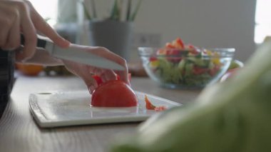 Sağlıklı Renkli Salata Hazırlığı İçin Taze Domates Kesen Eller. Domatesleri kesen kadınların ellerini sıcak mutfakta ev yapımı Vibrant salata için taze sebzelerle kesme tahtasına koy.