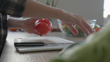 Taze ev yapımı sebze salatası için domates dilimleme tahtası. Parlak Mutfak 'ta Sağlıklı Malzemeleri Hazırlayan Ellerin Kapanışı. Yemek pişirme, Temiz Yemek ve Organik Yaşam Tarzı Konsepti