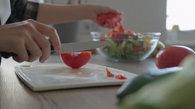 Renkli ev yapımı sebze salatasına taze domates dilimleri ekliyorum. Doğal bileşenleri olan sağlıklı organik pişirme konsepti, canlı renkler ve sıcak mutfak atmosferi. Yüksek kalite 4k görüntü