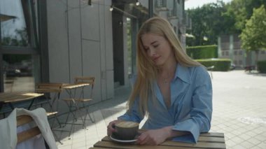 Barışçıl Sarışın Kadın, Cafe Spot 'ta sabah kahvesinin tadını çıkarıyor. Rahat Kadın Sıcak İçkinin Tadını Çıkartıyor Gün ışığında, Şehir Sabah Atmosferi, Huzurlu Yaşam Stili Anı