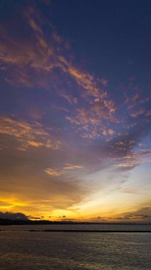Endonezya 'da çarpıcı bir günbatımı gökyüzünü canlı portakallar ve kırmızılarla boyar. İnsanlar toplanır, nefes kesici manzaranın ve huzurun tadını çıkarırlar..