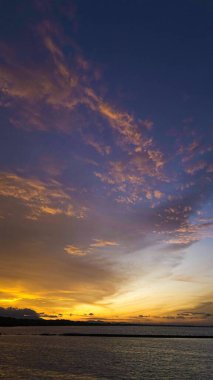 Endonezya 'da çarpıcı bir günbatımı gökyüzünü canlı portakallar ve kırmızılarla boyar. İnsanlar toplanır, nefes kesici manzaranın ve huzurun tadını çıkarırlar..