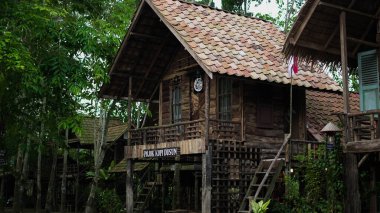 Ahşap ve betondan yapılmış, bir zamanlar Endonezya 'da bir evin ön kapısı olan açık bir duvarı olan küçük bir kahve dükkanı. En üst katta, kıvrımlı demir çarşaflardan yapılmış bir çatısı var..
