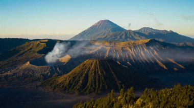 Bromo Dağı 'nda çarpıcı bir gündoğumu canlı bir günbatımını gözler önüne seriyor. Bulutlar zirveyi zarifçe kaplıyor ve Doğu Java' nın doğal güzelliğini gözler önüne seriyor..