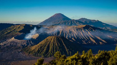 Bromo Dağı 'nda çarpıcı bir gündoğumu canlı bir günbatımını gözler önüne seriyor. Bulutlar zirveyi zarifçe kaplıyor ve Doğu Java' nın doğal güzelliğini gözler önüne seriyor..