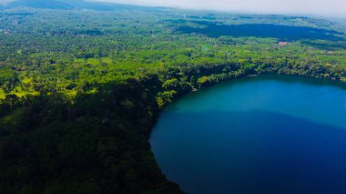 Doğu Java 'daki Ranu Bedali Gölü açık mavi bir gökyüzünün altında ışıldar ve arka planda Semeru Dağı görkemli bir şekilde yükselir. Çarpıcı bulutlar bu nefes kesici manzaranın dingin güzelliğini artırıyor..