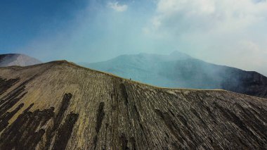 Havadan bakıldığında, Bromo Dağı 'nın kıyısında yürüyen, çarpıcı mavi gökyüzü ve serin, temiz havayla çevrili bir insan görülüyor..