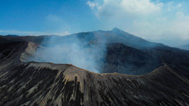 Havadan bakıldığında, Bromo Dağı 'nın kıyısında yürüyen, çarpıcı mavi gökyüzü ve serin, temiz havayla çevrili bir insan görülüyor..