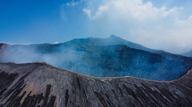 Havadan bakıldığında, Bromo Dağı 'nın kıyısında yürüyen, çarpıcı mavi gökyüzü ve serin, temiz havayla çevrili bir insan görülüyor..