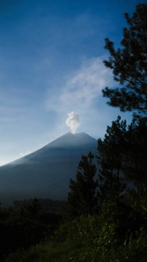 Capture the awe-inspiring view of Semeru Mountain from its foothills, where volcanic ash billows into the sky every minute. Surrounded by vibrant blue skies and diverse trees, clipart