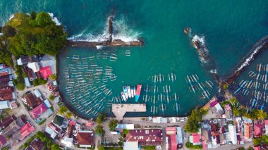 Yukarıdan yakalanan canlı balıkçı limanı Lampung 'u keşfedin. Renkli tekneler, berrak mavi suların arkaplanına karşı güzelce düzenlenmiştir. Limanı kaplayan büyüleyici evleri vardır.