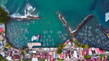 Yukarıdan yakalanan canlı balıkçı limanı Lampung 'u keşfedin. Renkli tekneler, berrak mavi suların arkaplanına karşı güzelce düzenlenmiştir. Limanı kaplayan büyüleyici evleri vardır.