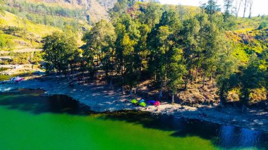 An aerial video from the summit of Rinjani shows the stunning Segara Anak Lake below. Surrounded by vibrant blue skies and clouds, the lake's serene beauty stands out against the dramatic landscape. clipart