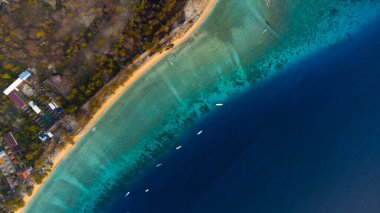 Güneş, açık mavi okyanustan yükselen Gili Trawangan 'ın üzerine altın bir parıltı saçar. Nefes kesici güzellik mükemmel bir tropikal sabah yaratır..
