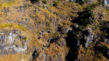 Rinjani Dağı 'nın zirvesine giden yolda yemyeşil ve kahverengi otlardan oluşan bir patika parlak mavi bir gökyüzünün altında uzanıyor. Dinlenme durakları güzergahta nokta.