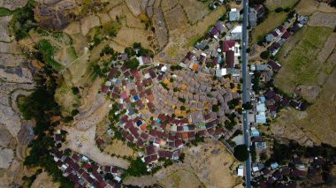 An aerial view of Sade Village in Lombok reveals lush farmland and densely populated homes under the bright midday sun, showcasing vibrant community life. clipart