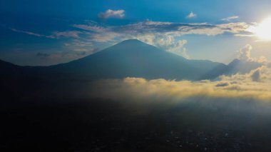 Sembalun 'da, Rinjani Dağı' nın eteklerindeki yuvarlanan tepelerin nefes kesen hava manzarası. Geniş savanalar gün doğumunda altın rengine dönüşüyor..