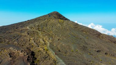 Tambora Dağı 'nın zirvesinin havadan görünüşü mavi gökyüzünün altında nefes kesen bir manzarayı gözler önüne seriyor, güneş doğarken, göz kamaştırıcı arazi üzerinde altın renkler seriyor..