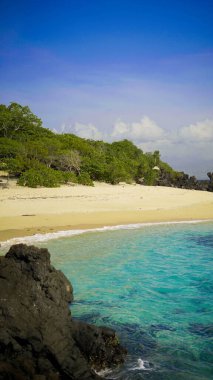 Adonara 'daki Ina Burak Sahili' nde, benzersiz siyah volkanik kaya oluşumları tarafından çerçevelenmiş berrak mavi sular ve yumuşak beyaz kumlar yer almaktadır..