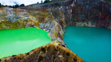 Experience the mesmerizing aerial view of Kelimutu's Three Color Lake in Ende. Wrapped in mystical clouds, this magical site, rich in legend, offers a breathtaking landscape that captivates the soul. clipart