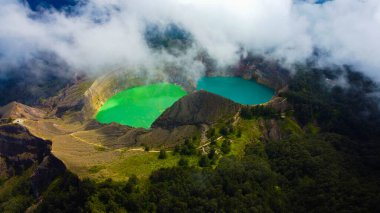 Experience the mesmerizing aerial view of Kelimutu's Three Color Lake in Ende. Wrapped in mystical clouds, this magical site, rich in legend, offers a breathtaking landscape that captivates the soul. clipart