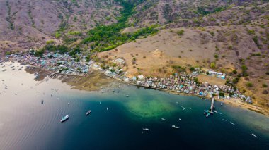Kampung Komodo, Endonezya 'da, berrak bir gökyüzünün altında canlı mavi sular uzanır. Huzurlu köy arkaplanı denizin çarpıcı, zengin maviliğiyle çelişiyor.