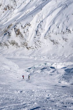 Two mail off-piste skiers stopping to admire a glacier while skiing Vallee Blanche in Chamonix, France. clipart