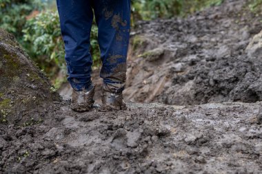 Çamurlu bir patikaya yakın çekim ve Khumbu, Nepal 'de hareketsiz duran çamurlu botları olan bir adam..