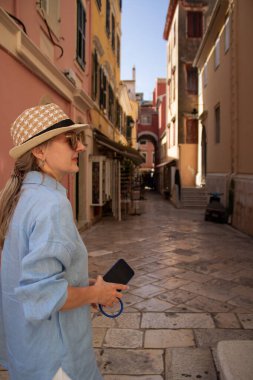 Genç bir turist kadın, Corfus 'un eski kasabası Kerkyra, Yunanistan' ın büyüleyici sokaklarını keşfederek, tarihi mimarinin ve canlı atmosferinin tadını çıkarıyor..