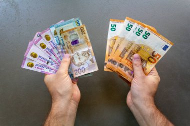 Man Holding Albanian Lek ve Euro Banknotes. Bir elinde Arnavut Lek 'i tutan bir adam ve diğer elinde Avro banknotları, para birimlerinin karşılaştırılması.
