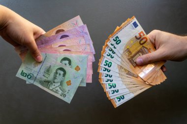 Kadın, Tayland Baht 'ını Avrupa' yla takas ediyor. Tayland Baht 'ı Euro banknotlarıyla değiştiren bir kadın. Küresel döviz kurunu sembolize ediyor..