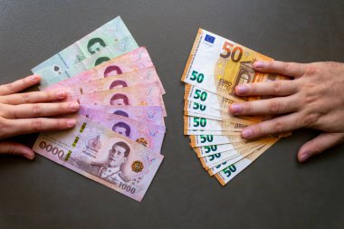 Kadın, Tayland Baht 'ını Avrupa' yla takas ediyor. Tayland Baht 'ı Euro banknotlarıyla değiştiren bir kadın. Küresel döviz kurunu sembolize ediyor..