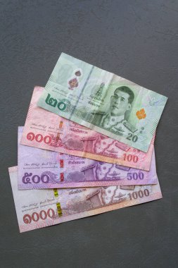 Tay Baht Banknotları. Tayland Baht banknotlarının yakın plan çekimleri bir masaya yayılarak, para birimini vurguluyor.