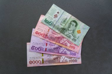 Tay Baht Banknotları. Tayland Baht banknotlarının yakın plan çekimleri bir masaya yayılarak, para birimini vurguluyor.