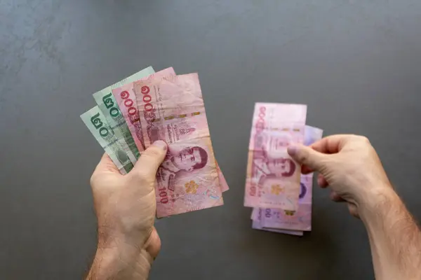 Tayland Baht Banknotları Sayan Adam. Elinde bir yığın Tayland Baht banknotunu tutan ve sayan bir adam, ellerine ve parasına odaklan..