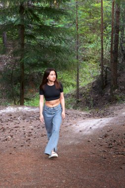 Ağaçlar ve yeşilliklerle çevrili ormanda yalnız yürüyen genç bir kadın yalnızlığı ve doğanın huzurunu kucaklıyor. Özgürlük kavramı, kendi yansıması ve açık hava yaşam tarzı..