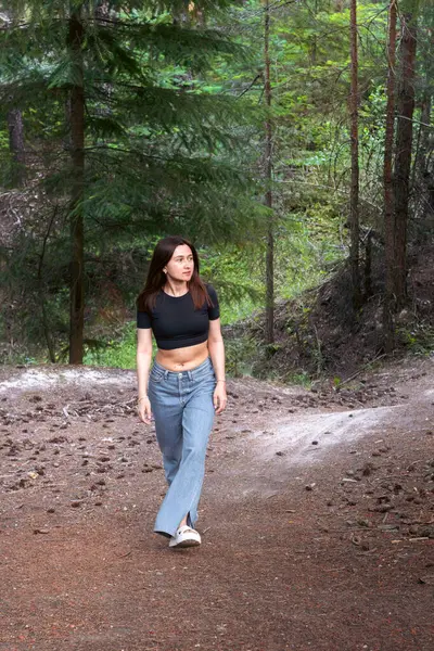 Ağaçlar ve yeşilliklerle çevrili ormanda yalnız yürüyen genç bir kadın yalnızlığı ve doğanın huzurunu kucaklıyor. Özgürlük kavramı, kendi yansıması ve açık hava yaşam tarzı..