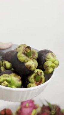 Beyaz kase taze, olgun mangosenlerle dolup taşıyor. Derin mor derileri ve canlı yeşil kalixleri Vietnam 'da yaz için mükemmel, lezzetli, sağlıklı ve egzotik bir ziyafet oluşturur..