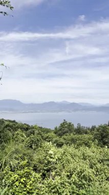 Yukarıdan çarpıcı panoramik bir tropik körfez manzarası. Bereketli yeşiller, uzak adalar ve açık mavi sulardaki dağlar yaz gökyüzünün altında. Bn o Sn Tr, Da Nang, Vietnam