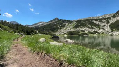 Bulgaristan 'ın Pirin Dağı' nda güzel bir yaz günü dingin bir alp gölü ve yemyeşil çayırlar ve görkemli tepeler arasında dolambaçlı bir yürüyüş yolu sergiliyor..